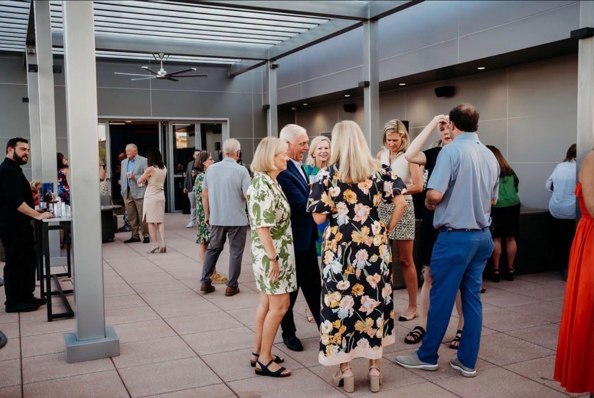 Guests mingling and chatting on a rooftop terrace during a cocktail hour
